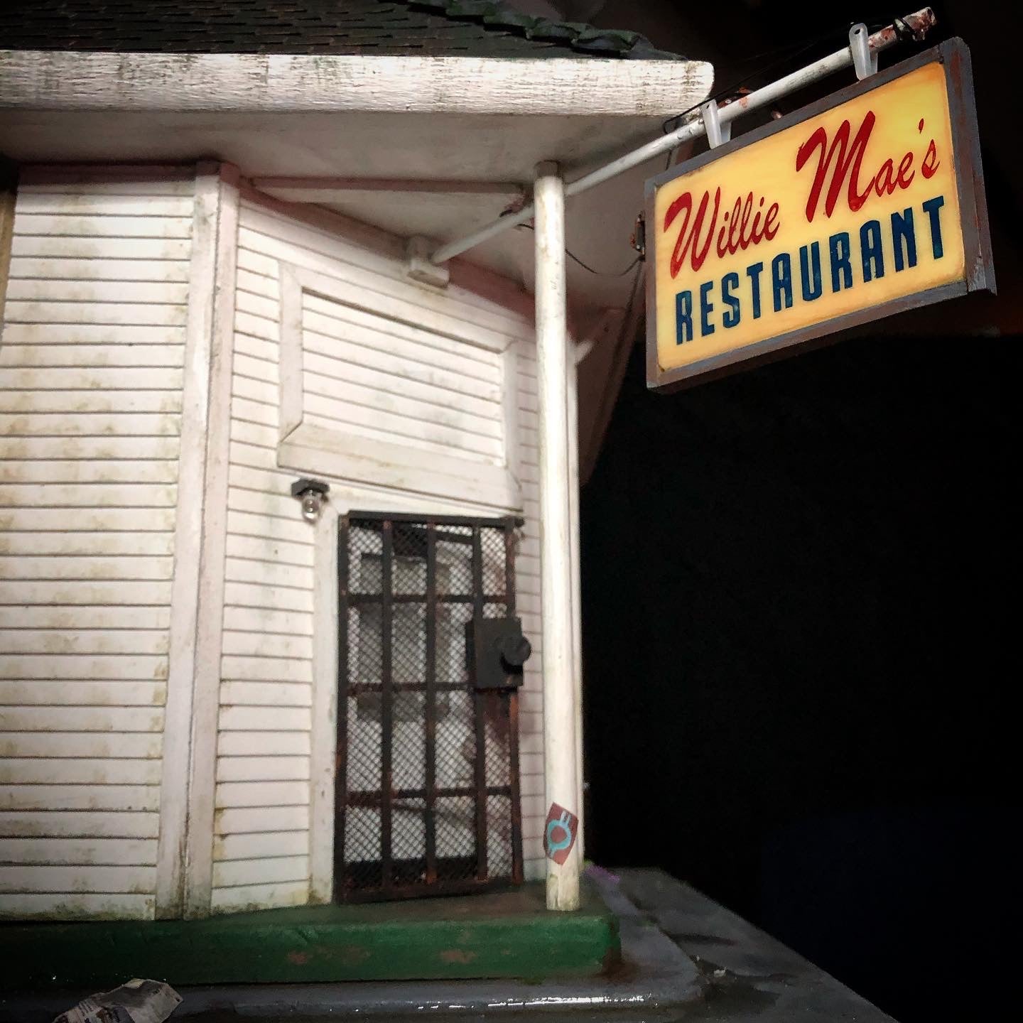 Close up photo showing a miniature model of Willie Mae's restaurant sign hanging out front of the restaurant. 