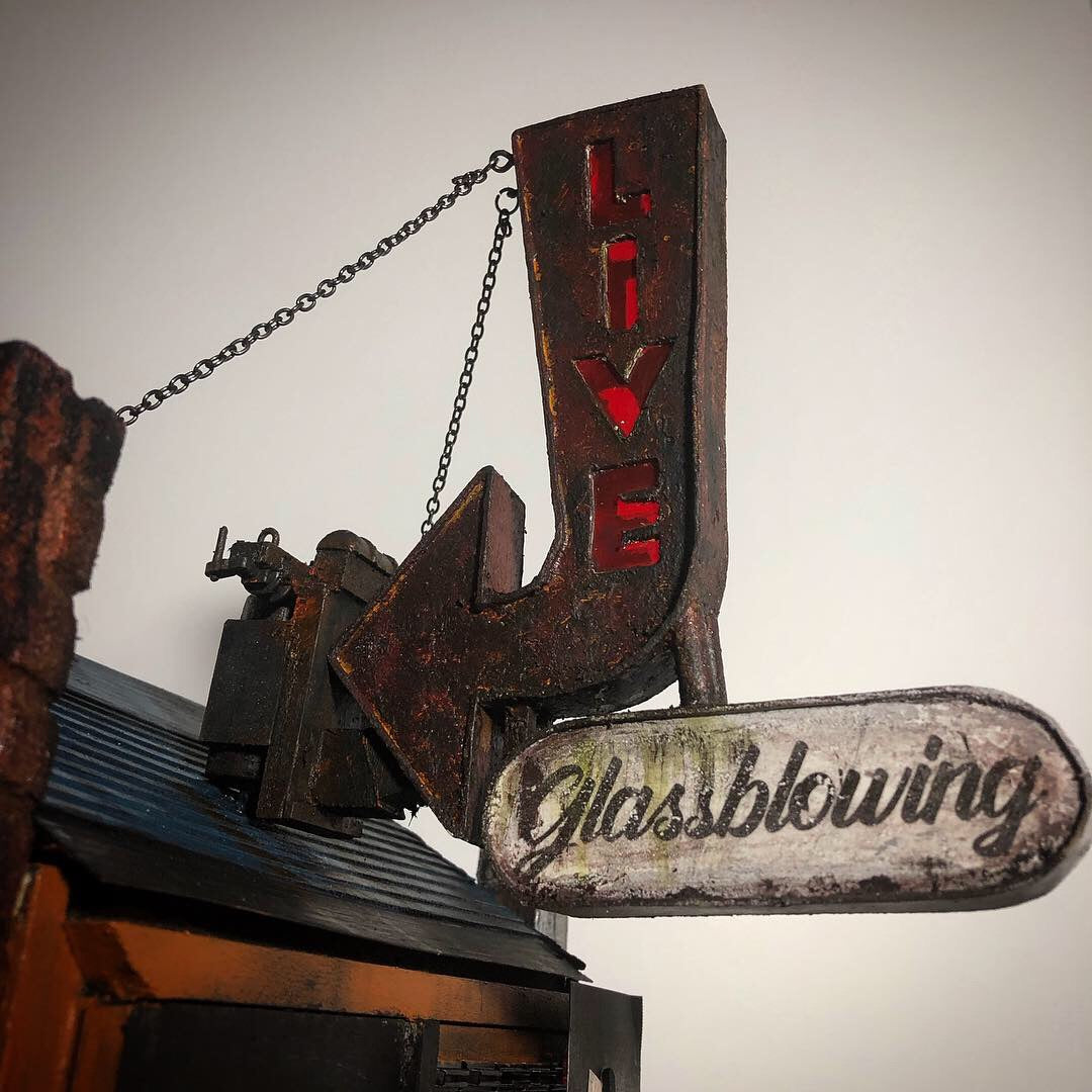 Close up photo of a miniature model, showing a Live Glassblowing Sign. 