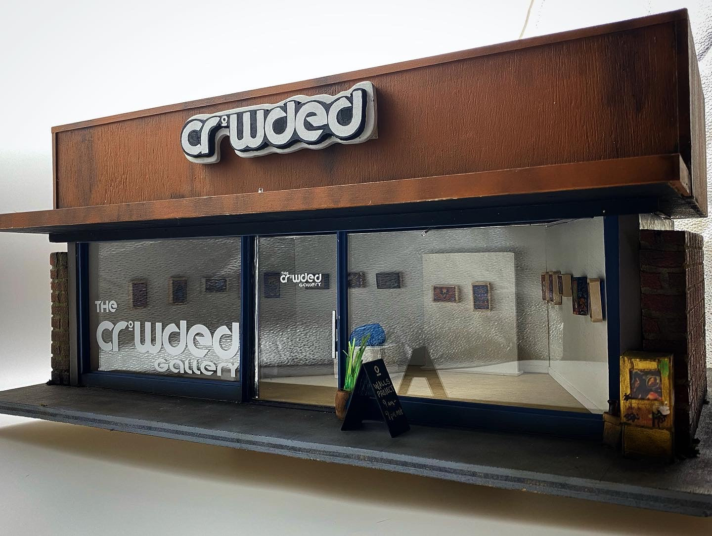 Photo showing the Crowded Gallery Miniature Model, a tiny scale model of a gallery showing art on the walls. 