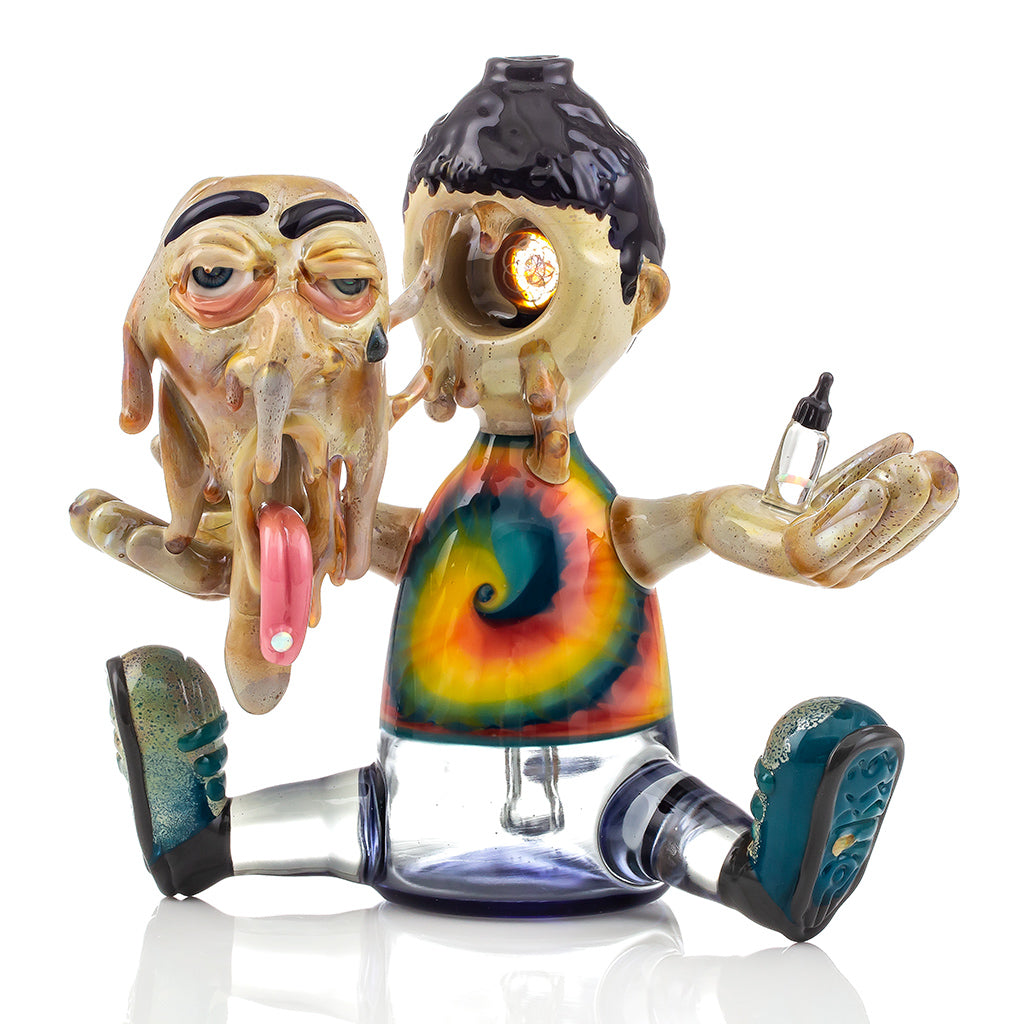 Studio photo of a R3G15 Heady Glass Piece, piece has a dripping face with opal lsd tab on tongue and tie dye shirt. 
