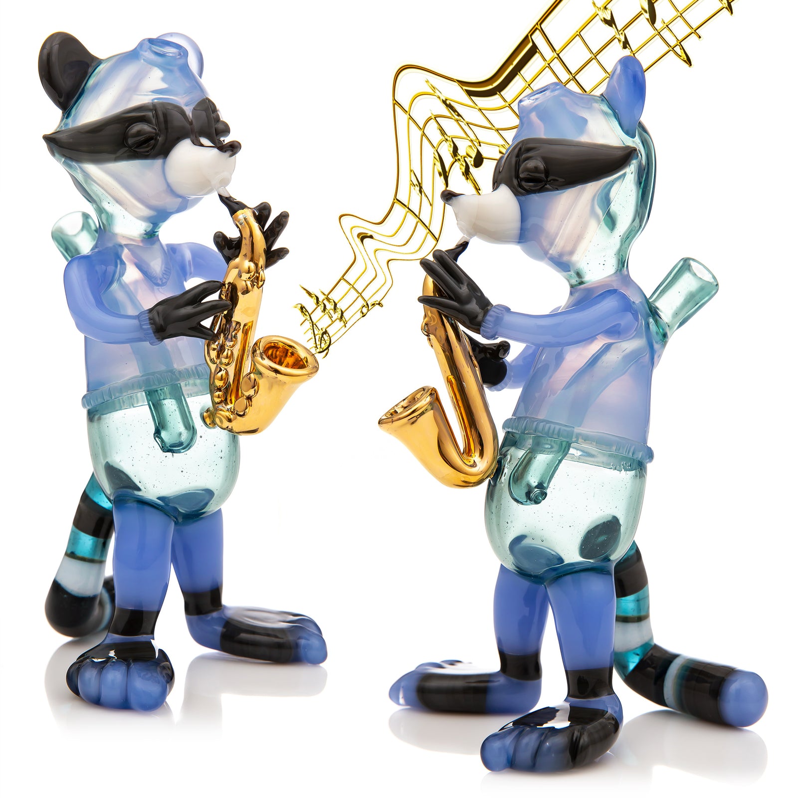 Studio photo showing two different views of a heady glass raccoon piece the R3g15 made, the piece is a gold plated saxophone player, there are gold notes edited coming out of the instrument in one angle. 