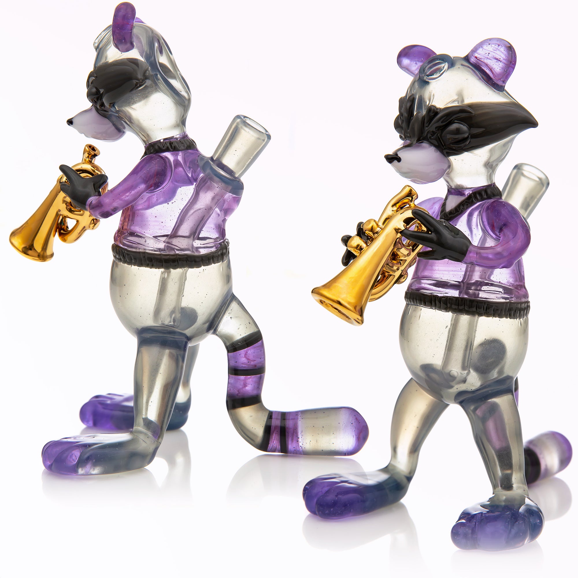 Two separate angles are shown in a studio photo edit of a heady glass raccoon piece by R3G15, the piece is a purple and grey raccoon playing a gold plated trumpet. 